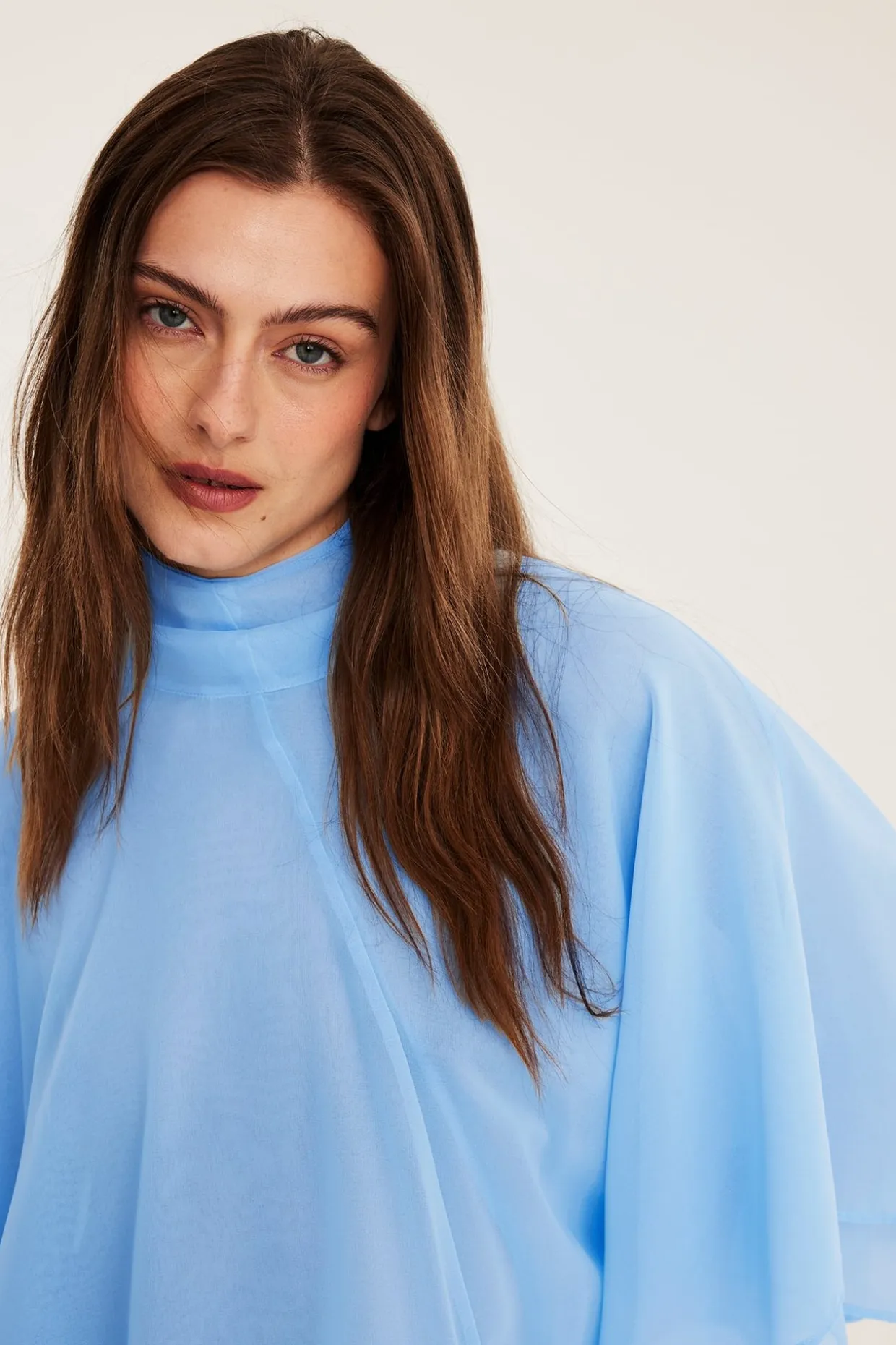 Chiffongblus med cape‑silhuett