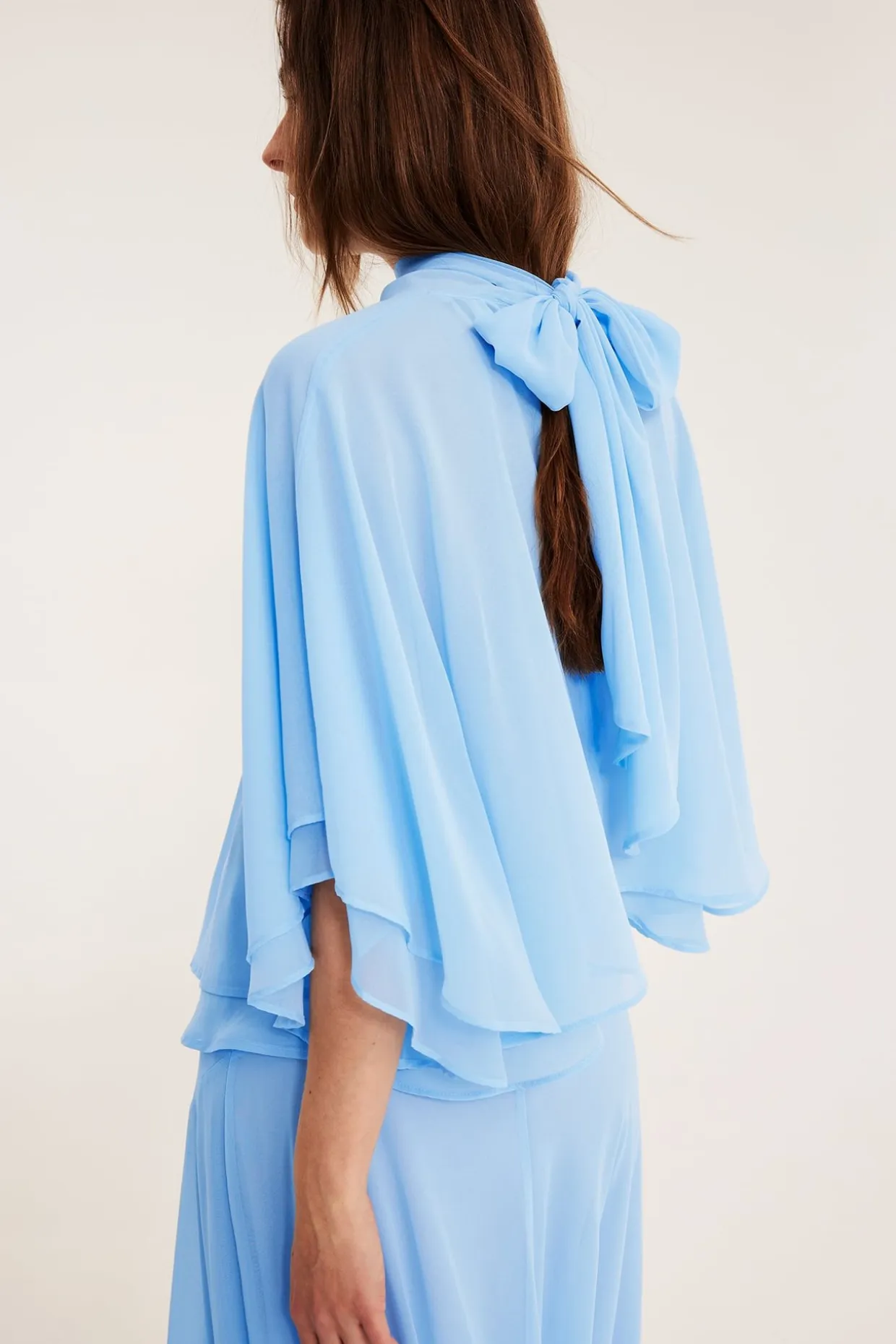 Chiffongblus med cape‑silhuett